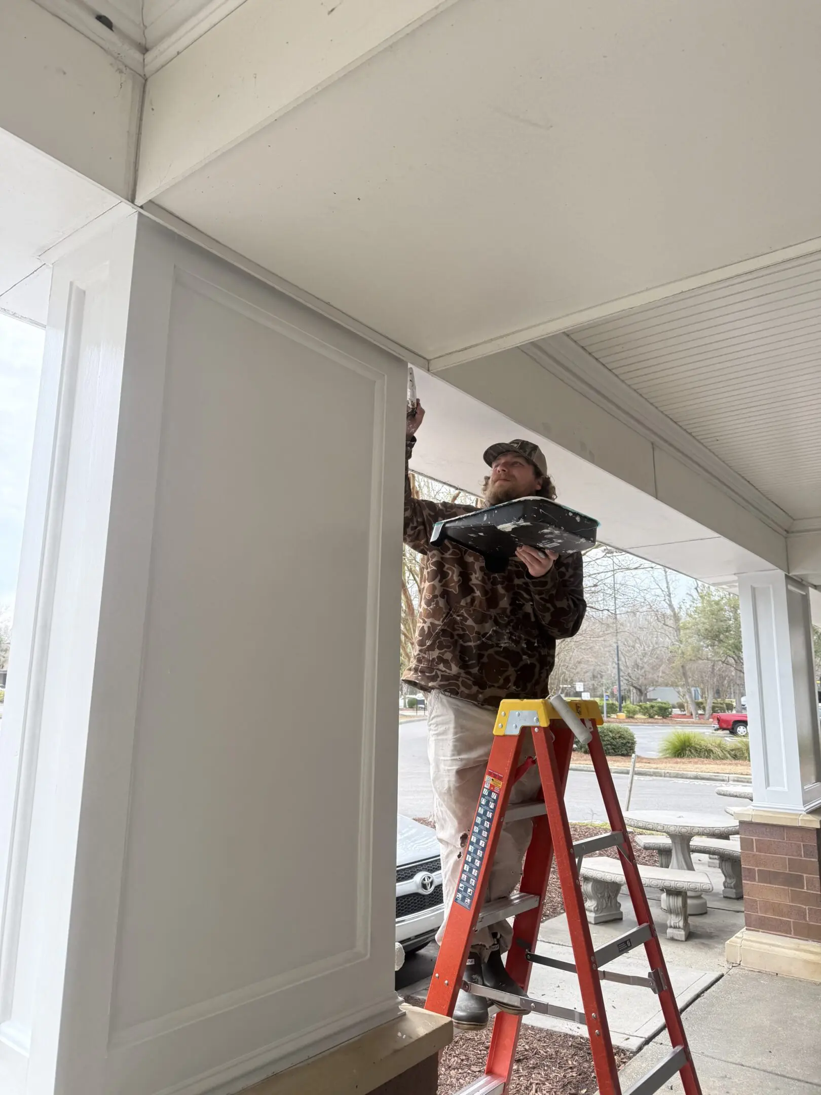 Man on ladder installing or fixing a door frame.