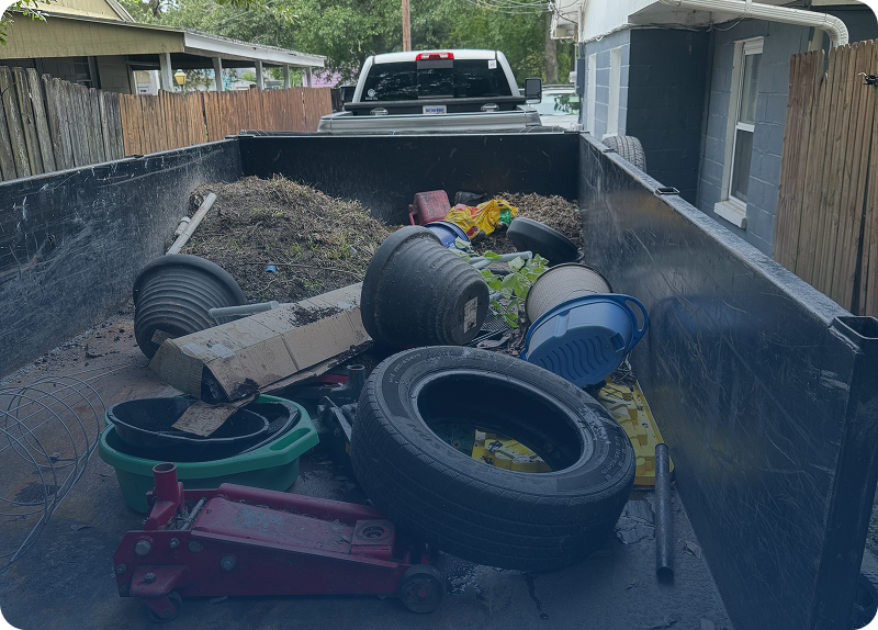 Old tires and debris in a trailer bed beside a white truck.