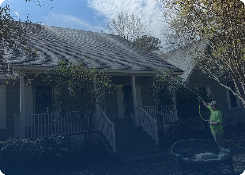 A front porch of a house with a railing and leafless trees nearby.