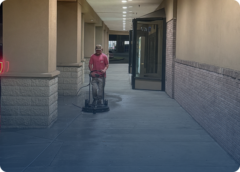 A man operating a floor polishing machine in a corridor.