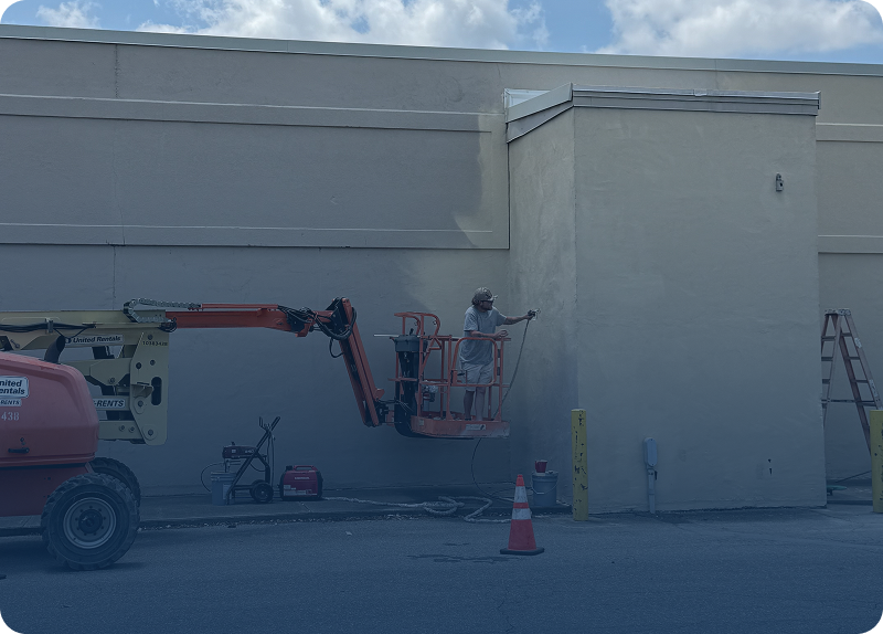 Workers painting the exterior of a building using a lift.