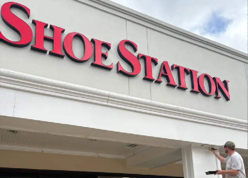Storefront sign displaying 'SHOE STATION' in red letters on a white building.