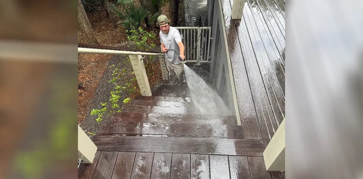 Person power washing wooden stairs outdoors.